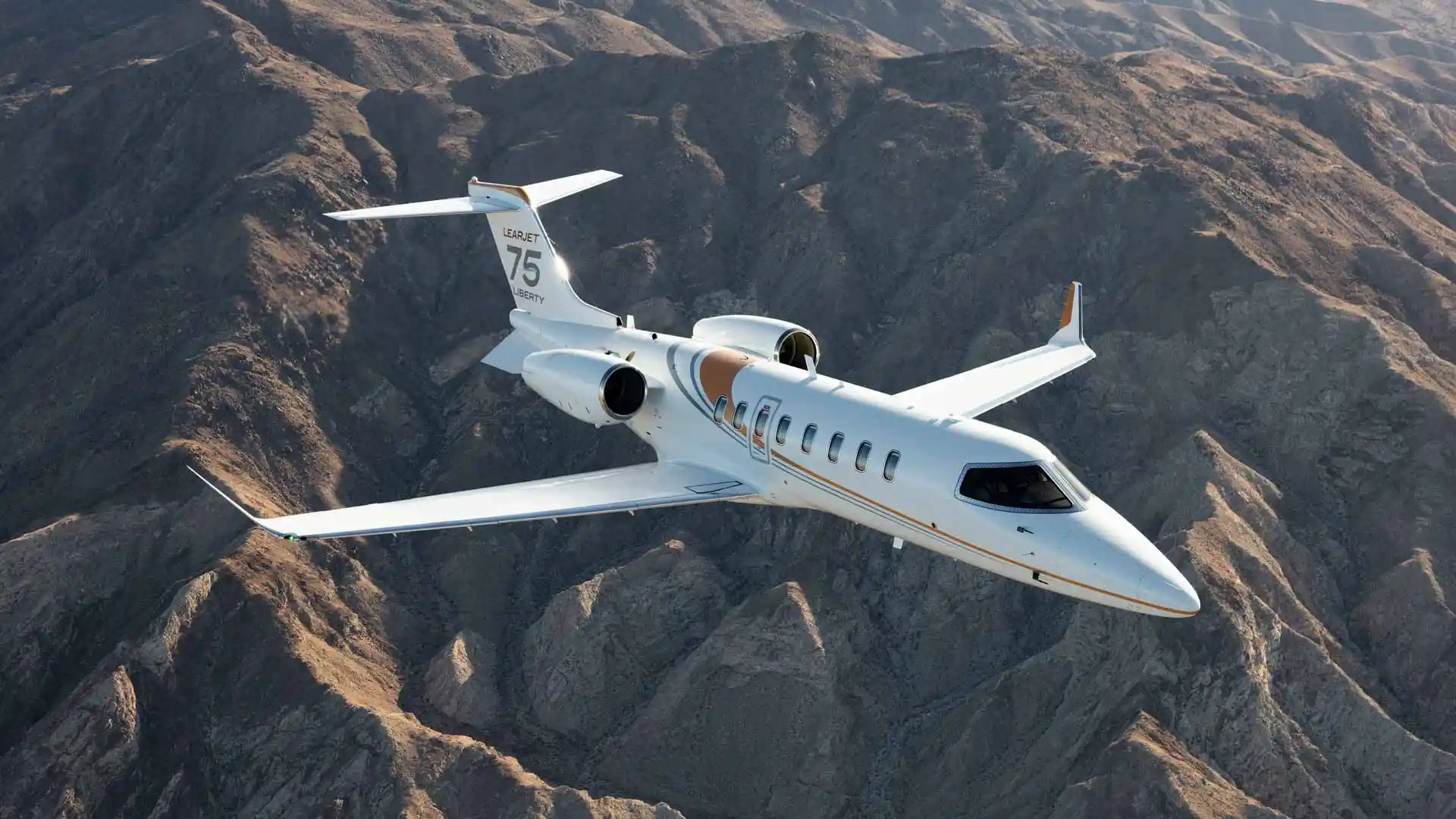 Learjet 75 in flight over desert mountains