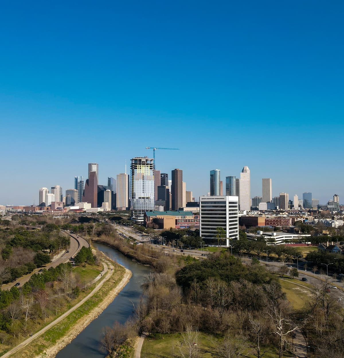 Downtown Houston skyline beyond a bayou and parkland