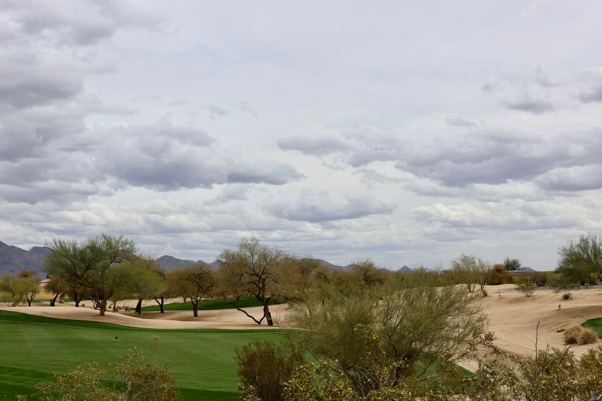 Desert golf course under a cloudy sky in Scottsdale, with mountains beyond
